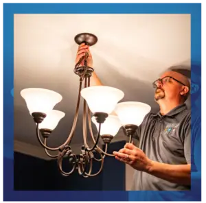 Electrician installing or repairing a chandelier in a home.